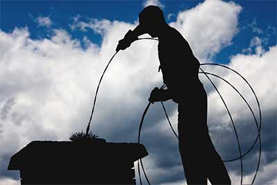 Chimney service in Lacey, chimney sweep profile on roof with brush