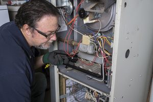 Furnace repair Manasquan technician in front of opened furnace