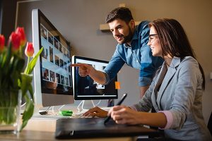 Web design Long Beach Island company working with client in front of two monitors reviewing photos