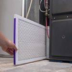 New air filter being installed into a furnace to help avoid furnace repair Manasquan