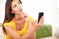 Woman holding cell phone with a questioning look on her face while browsing Lavallette real estate